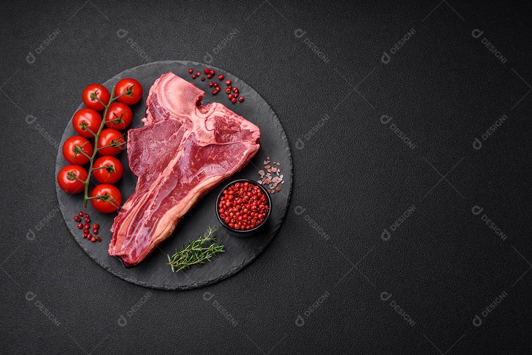 Bife de carne crua e suculenta com sal, especiarias e ervas sobre um fundo escuro de concreto