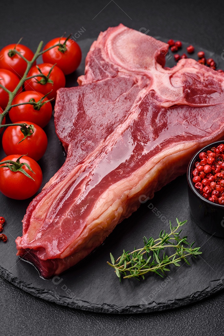 Bife de carne crua e suculenta com sal, especiarias e ervas sobre um fundo escuro de concreto