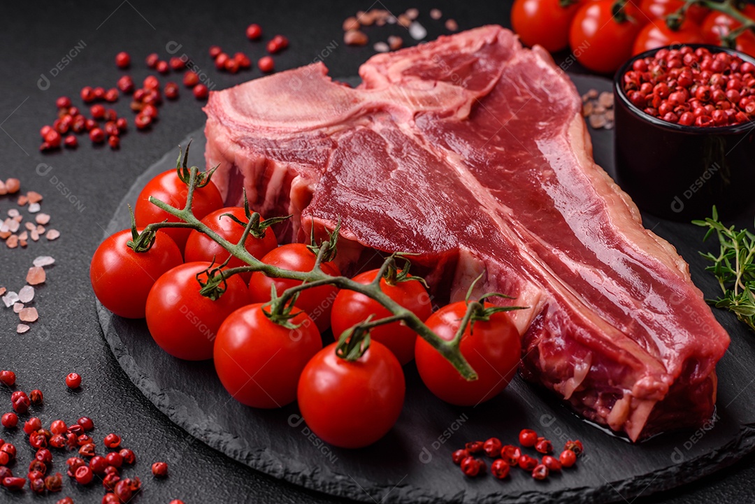 Bife de carne crua e suculenta com sal, especiarias e ervas sobre um fundo escuro de concreto