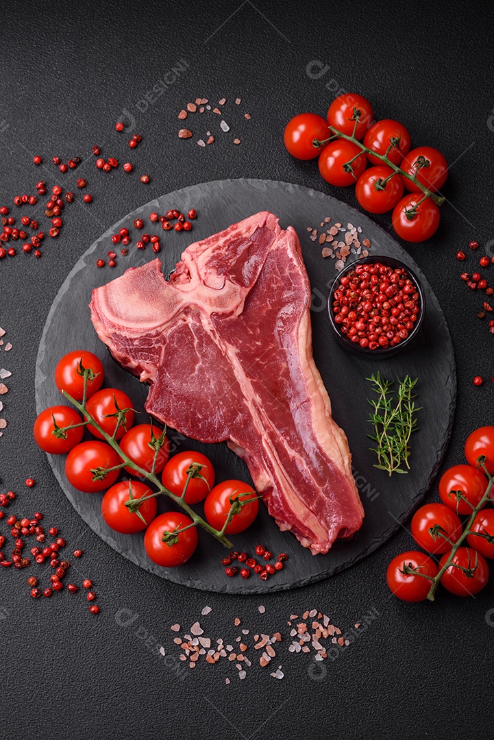 Bife de carne crua e suculenta com sal, especiarias e ervas sobre um fundo escuro de concreto