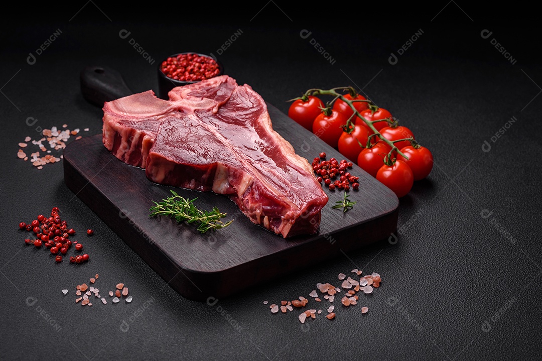Bife de carne crua e suculenta com sal, especiarias e ervas sobre um fundo escuro de concreto