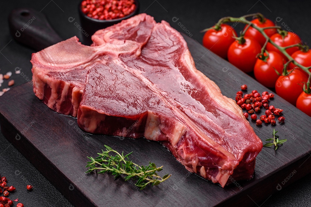 Bife de carne crua e suculenta com sal, especiarias e ervas sobre um fundo escuro de concreto