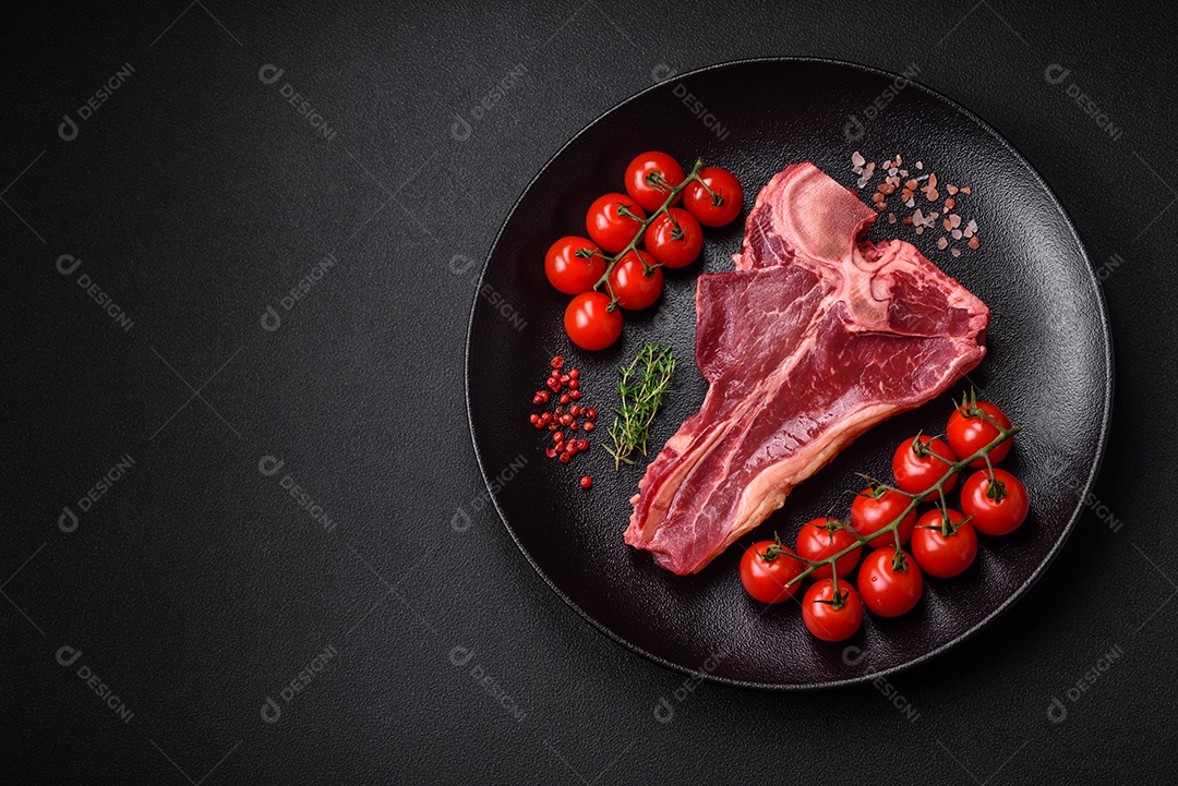 Bife de carne crua e suculenta com sal, especiarias e ervas sobre um fundo escuro de concreto