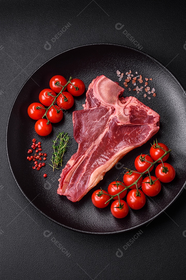 Bife de carne crua e suculenta com sal, especiarias e ervas sobre um fundo escuro de concreto