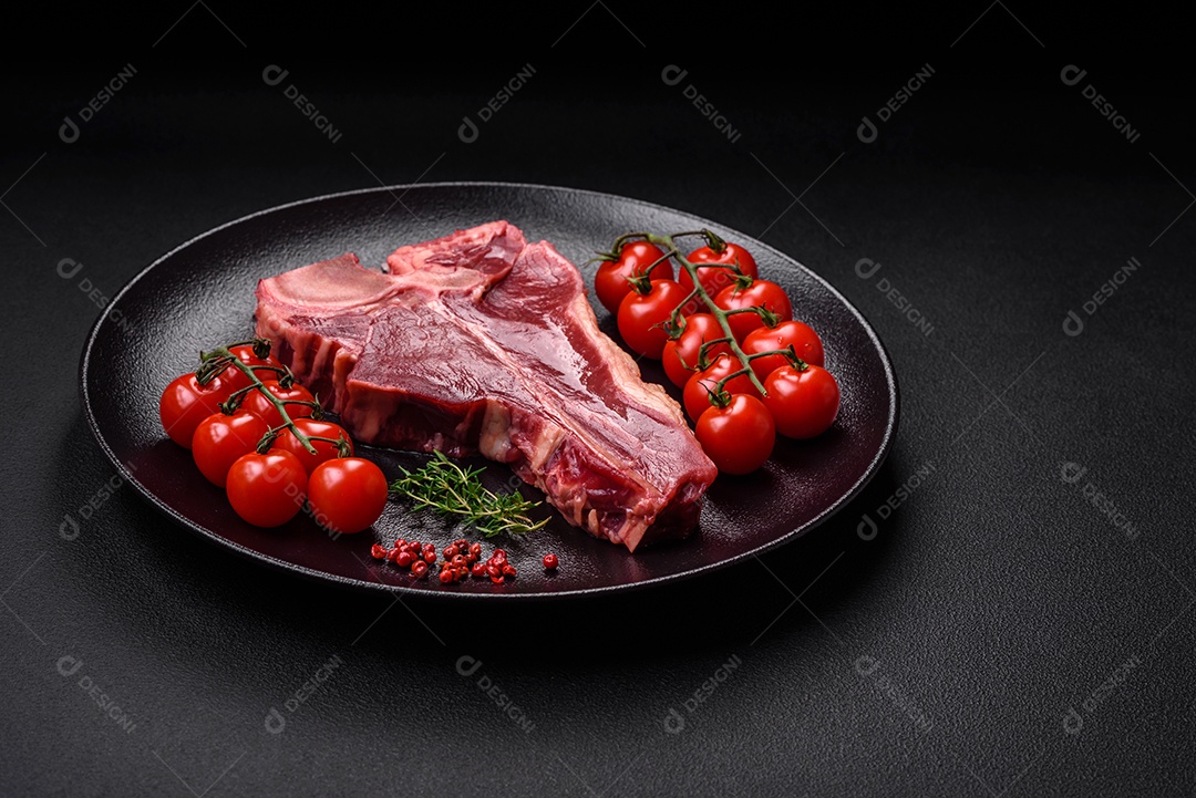 Bife de carne crua e suculenta com sal, especiarias e ervas sobre um fundo escuro de concreto