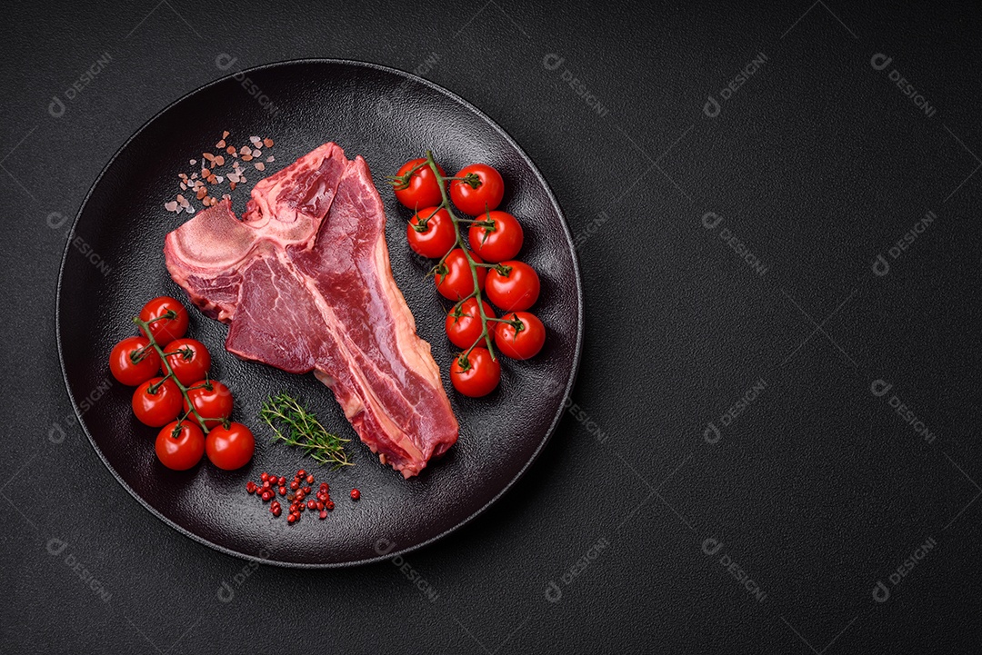 Bife de carne crua e suculenta com sal, especiarias e ervas sobre um fundo escuro de concreto