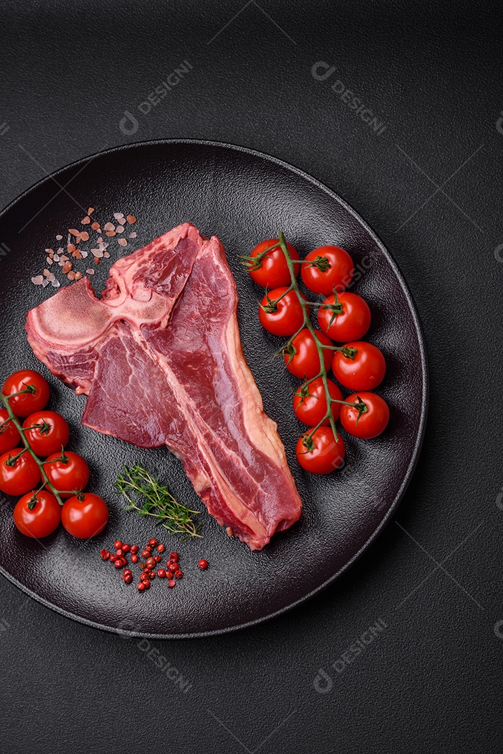 Bife de carne crua e suculenta com sal, especiarias e ervas sobre um fundo escuro de concreto