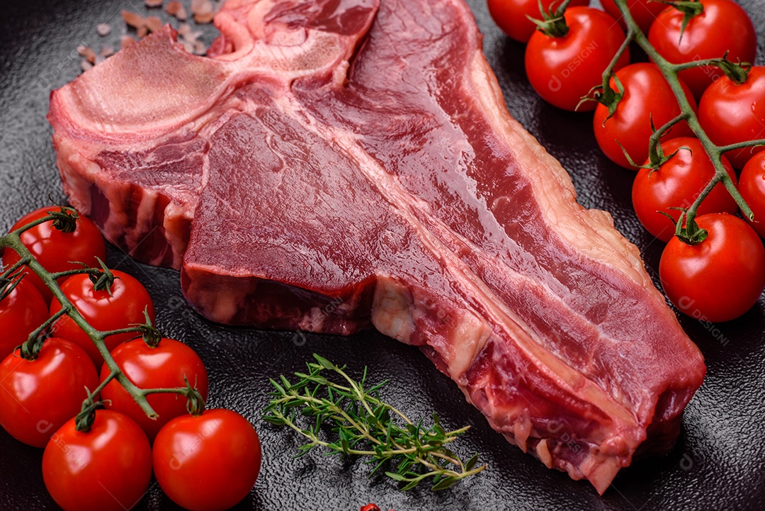 Bife de carne crua e suculenta com sal, especiarias e ervas sobre um fundo escuro de concreto
