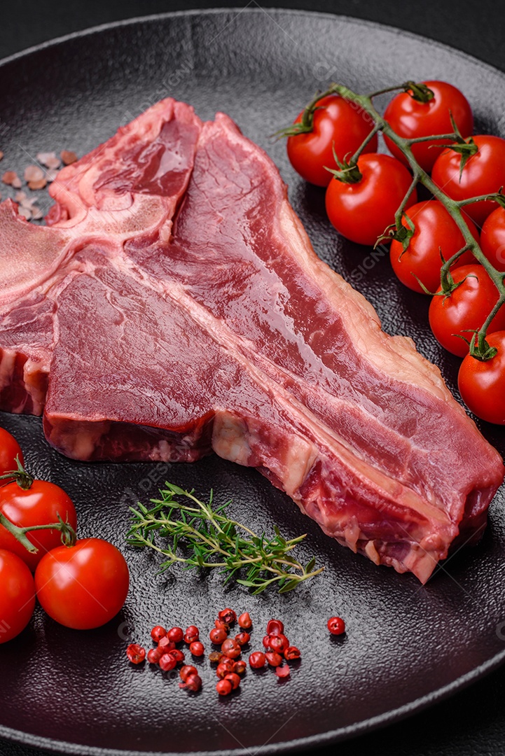Bife de carne crua e suculenta com sal, especiarias e ervas sobre um fundo escuro de concreto