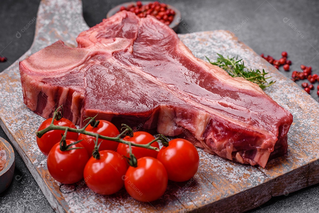 Bife de carne crua e suculenta com sal, especiarias e ervas sobre um fundo escuro de concreto