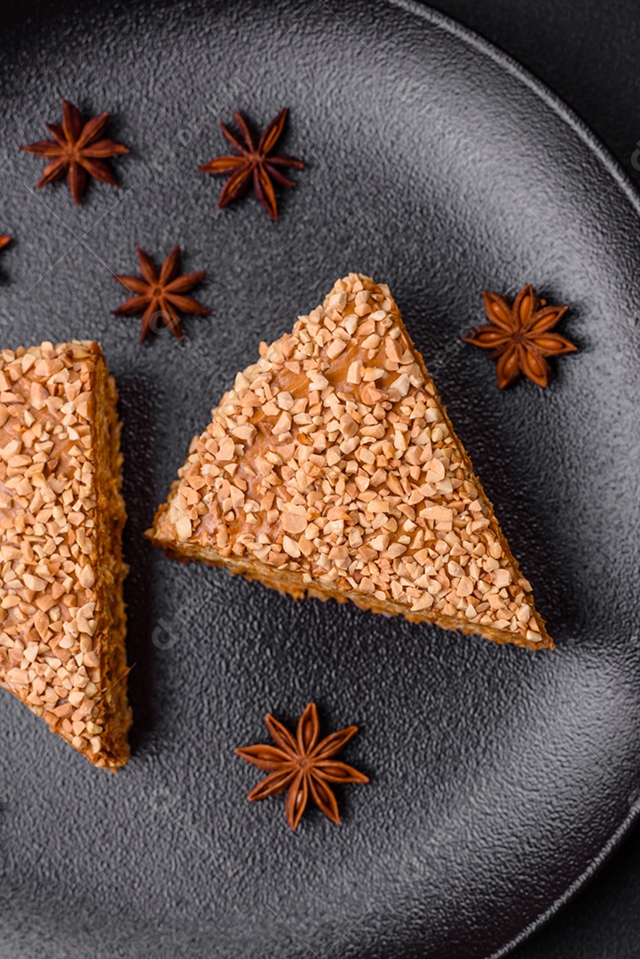 Delicioso bolo de waffle doce com creme e nozes cortados em pedaços sobre um fundo de concreto texturizado