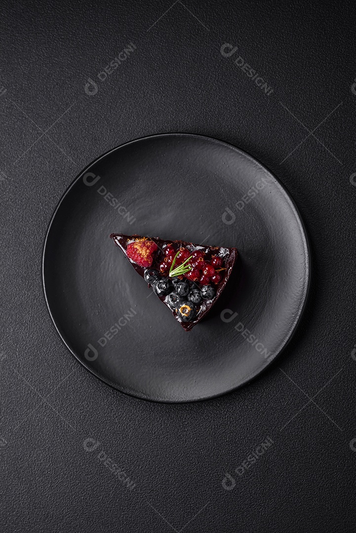 Delicioso bolo de brownie de chocolate doce com mirtilos, groselhas e framboesas num prato de cerâmica