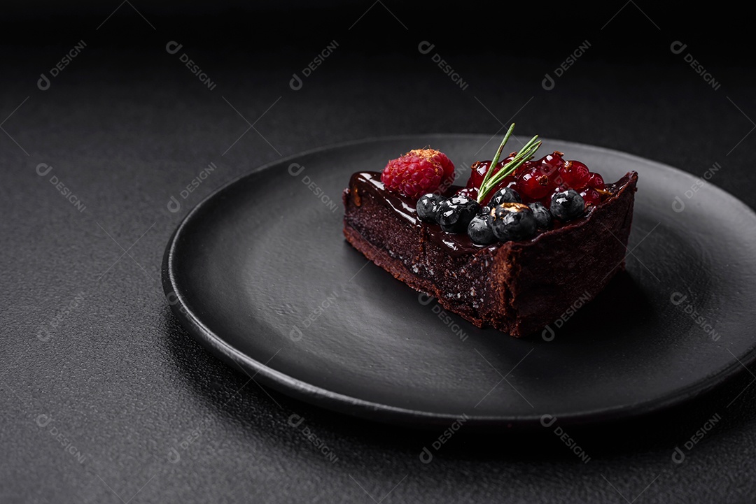 Delicioso bolo de brownie de chocolate doce com mirtilos, groselhas e framboesas num prato de cerâmica