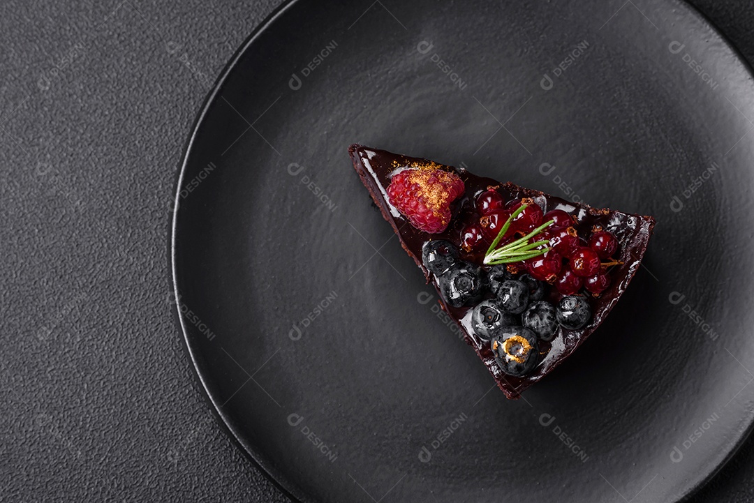 Delicioso bolo de brownie de chocolate doce com mirtilos, groselhas e framboesas num prato de cerâmica