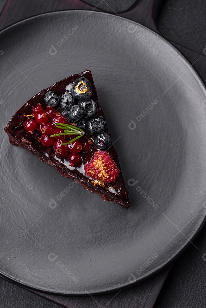 Delicioso bolo de brownie de chocolate doce com mirtilos, groselhas e framboesas num prato de cerâmica