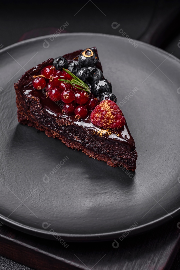 Delicioso bolo de brownie de chocolate doce com mirtilos, groselhas e framboesas num prato de cerâmica