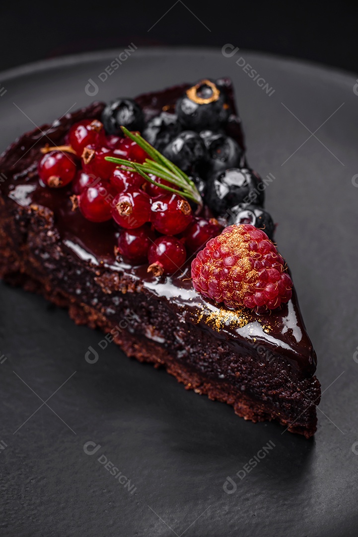 Delicioso bolo de brownie de chocolate doce com mirtilos, groselhas e framboesas num prato de cerâmica