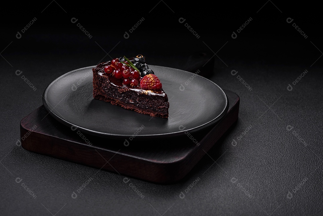 Delicioso bolo de brownie de chocolate doce com mirtilos, groselhas e framboesas num prato de cerâmica