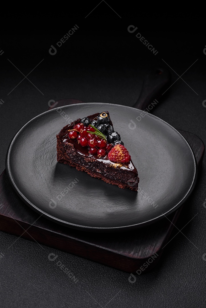 Delicioso bolo de brownie de chocolate doce com mirtilos, groselhas e framboesas num prato de cerâmica