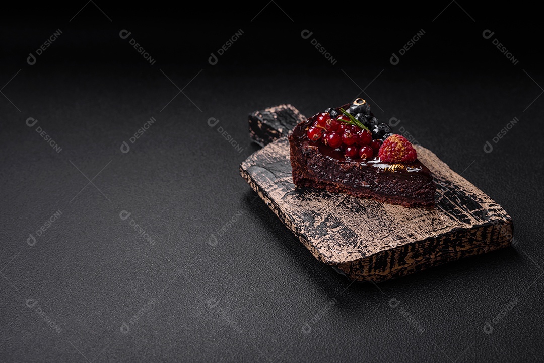 Delicioso bolo de brownie de chocolate doce com mirtilos, groselhas e framboesas num prato de cerâmica