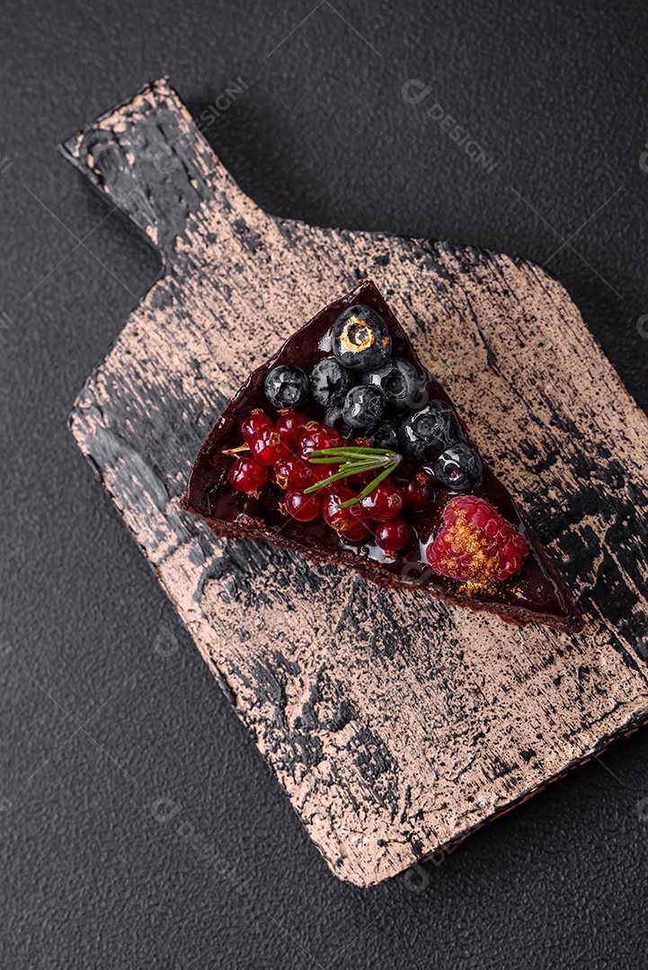 Delicioso bolo de brownie de chocolate doce com mirtilos, groselhas e framboesas num prato de cerâmica