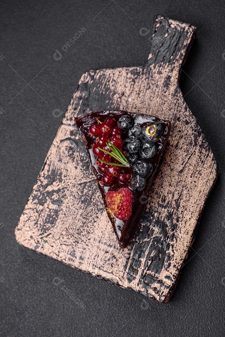 Delicioso bolo de brownie de chocolate doce com mirtilos, groselhas e framboesas num prato de cerâmica