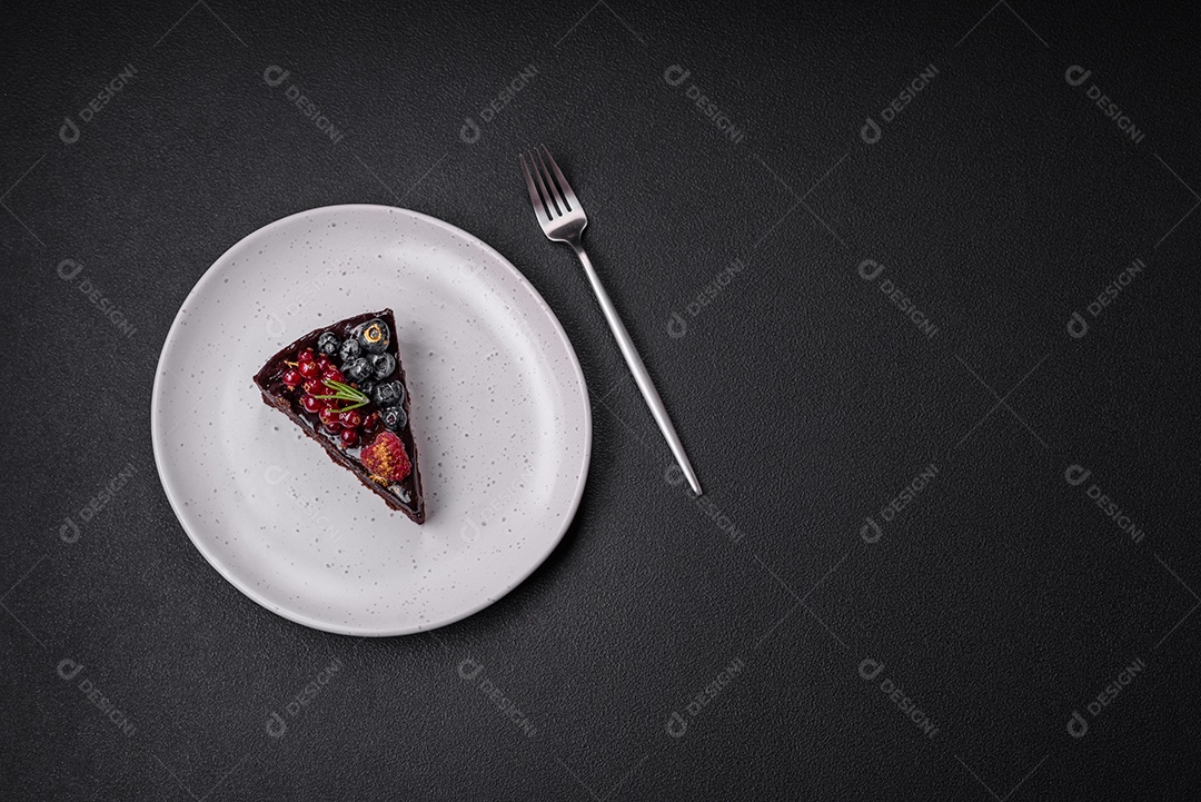 Delicioso bolo de brownie de chocolate doce com mirtilos, groselhas e framboesas num prato de cerâmica