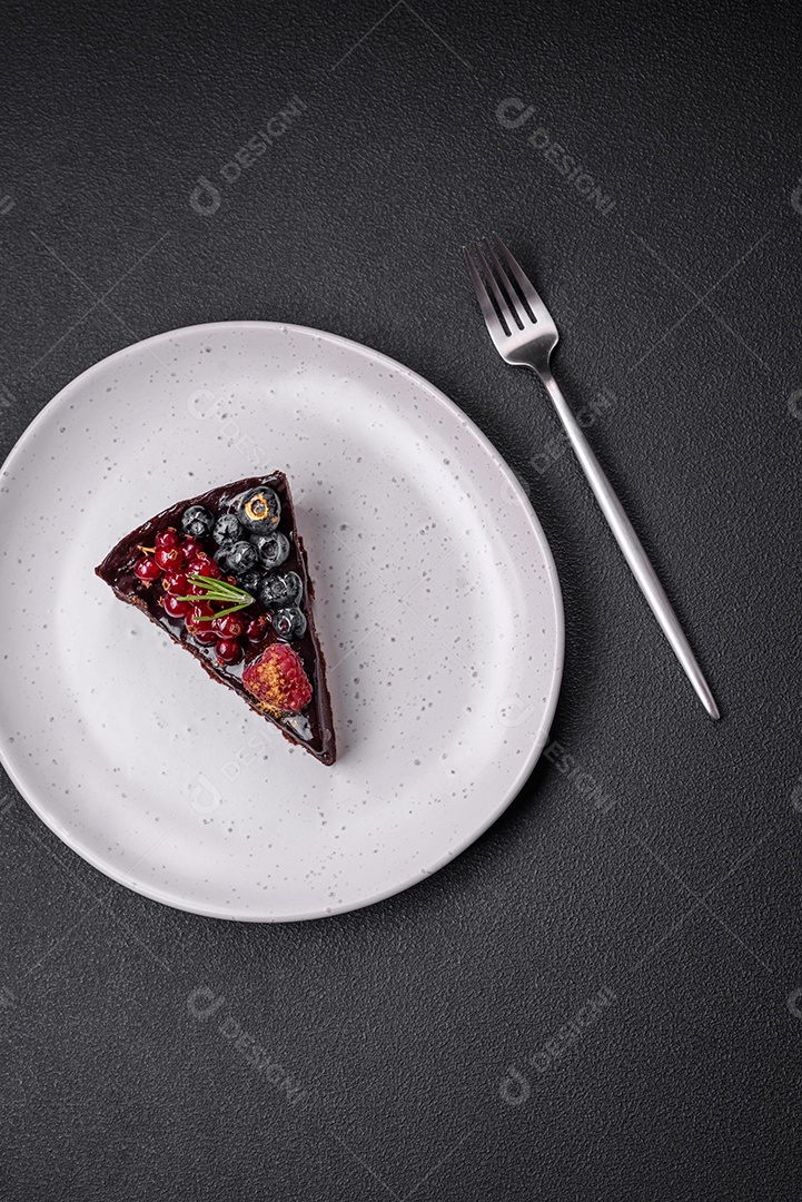 Delicioso bolo de brownie de chocolate doce com mirtilos, groselhas e framboesas num prato de cerâmica