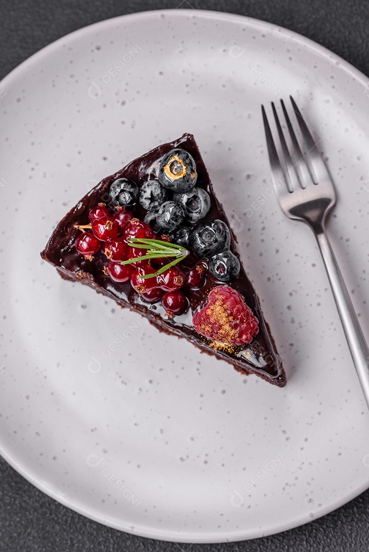 Delicioso bolo de brownie de chocolate doce com mirtilos, groselhas e framboesas num prato de cerâmica