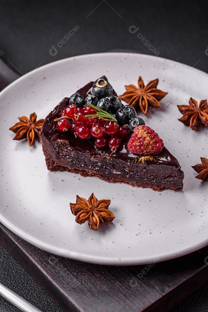 Delicioso bolo de brownie de chocolate doce com mirtilos, groselhas e framboesas num prato de cerâmica