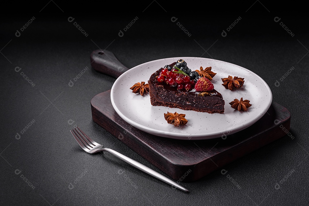 Delicioso bolo de brownie de chocolate doce com mirtilos, groselhas e framboesas num prato de cerâmica