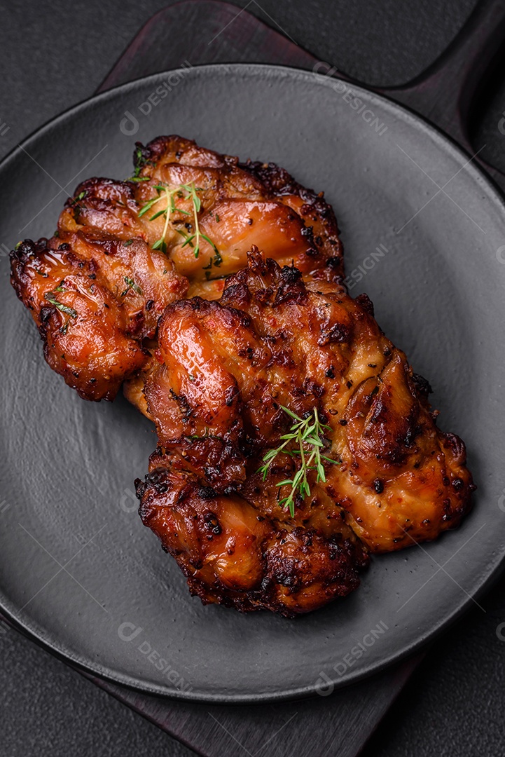 Deliciosa carne de frango assada com sal, especiarias e ervas sobre um fundo escuro de concreto