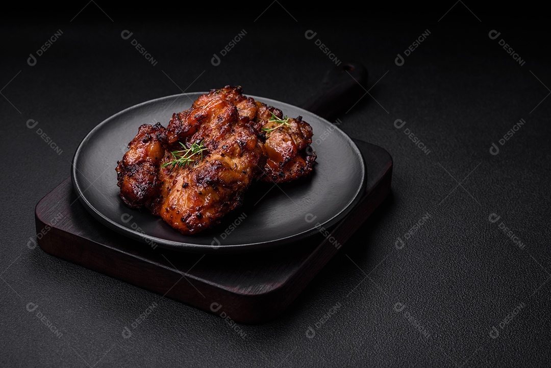 Deliciosa carne de frango assada com sal, especiarias e ervas sobre um fundo escuro de concreto