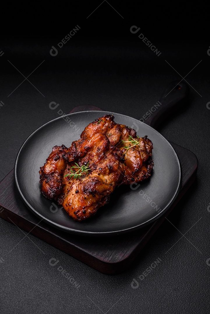 Deliciosa carne de frango assada com sal, especiarias e ervas sobre um fundo escuro de concreto