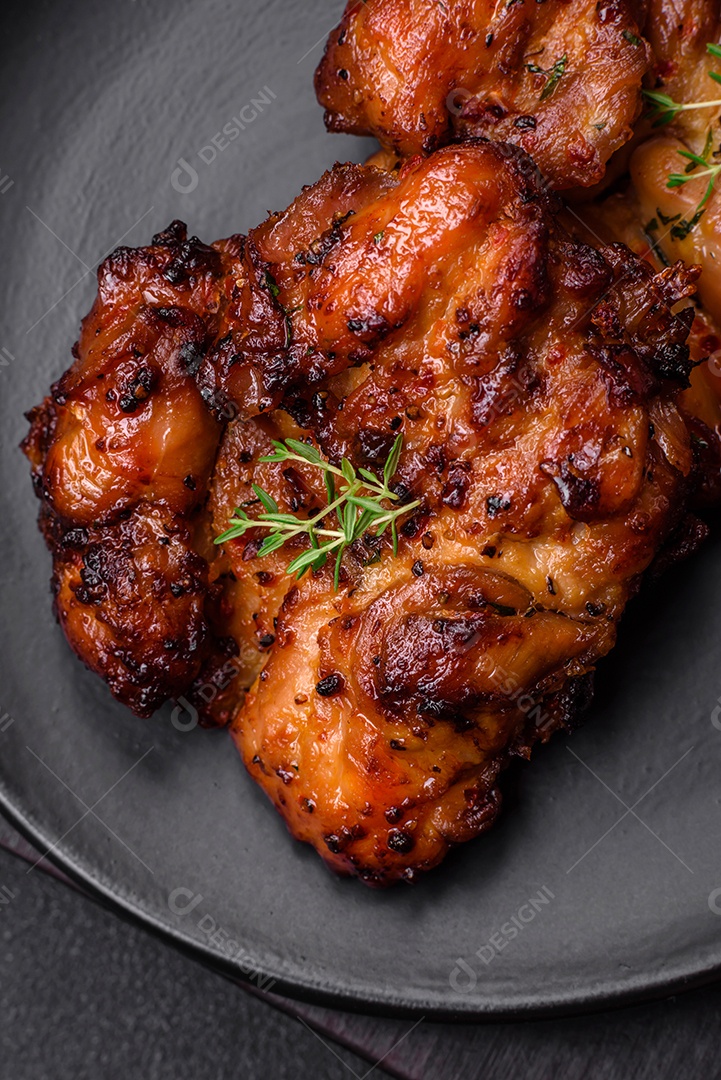 Deliciosa carne de frango assada com sal, especiarias e ervas sobre um fundo escuro de concreto