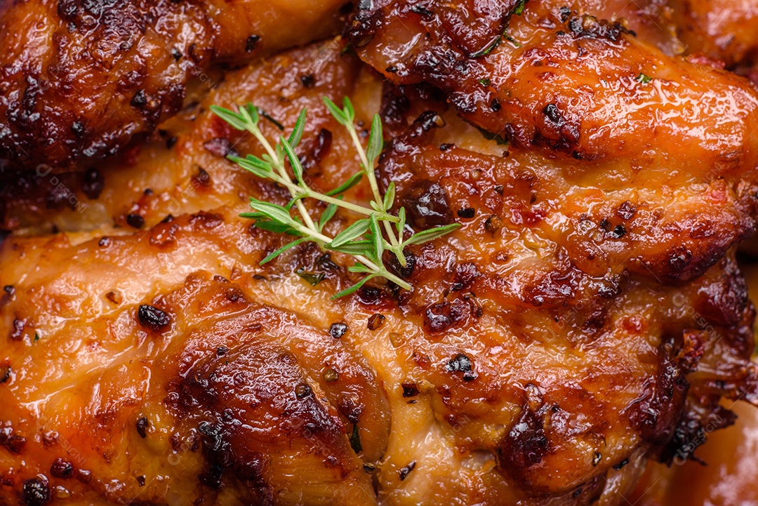 Deliciosa carne de frango assada com sal, especiarias e ervas sobre um fundo escuro de concreto