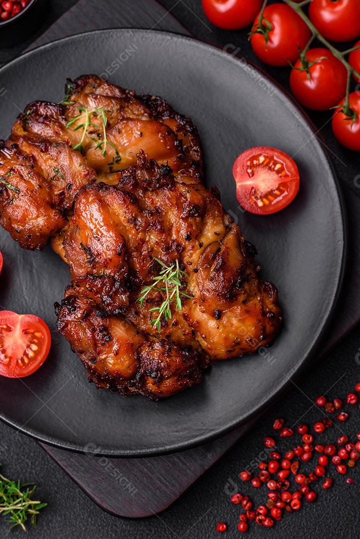 Deliciosa carne de frango assada com sal, especiarias e ervas sobre um fundo escuro de concreto