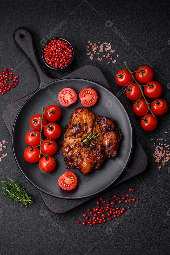 Deliciosa carne de frango assada com sal, especiarias e ervas sobre um fundo escuro de concreto