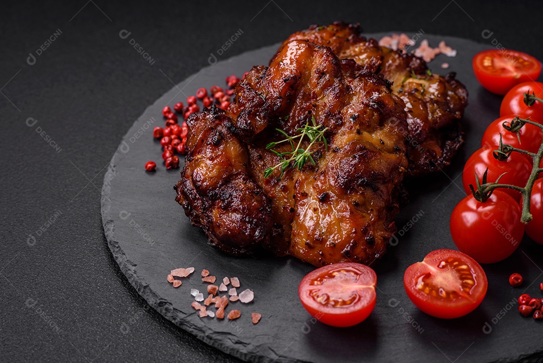Deliciosa carne de frango assada com sal, especiarias e ervas sobre um fundo escuro de concreto