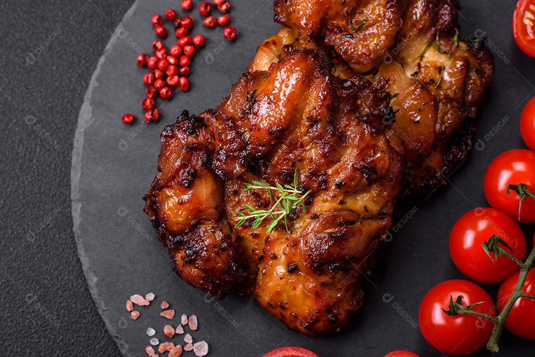 Deliciosa carne de frango assada com sal, especiarias e ervas sobre um fundo escuro de concreto