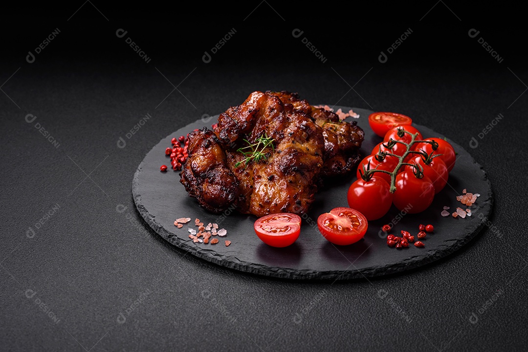 Deliciosa carne de frango assada com sal, especiarias e ervas sobre um fundo escuro de concreto