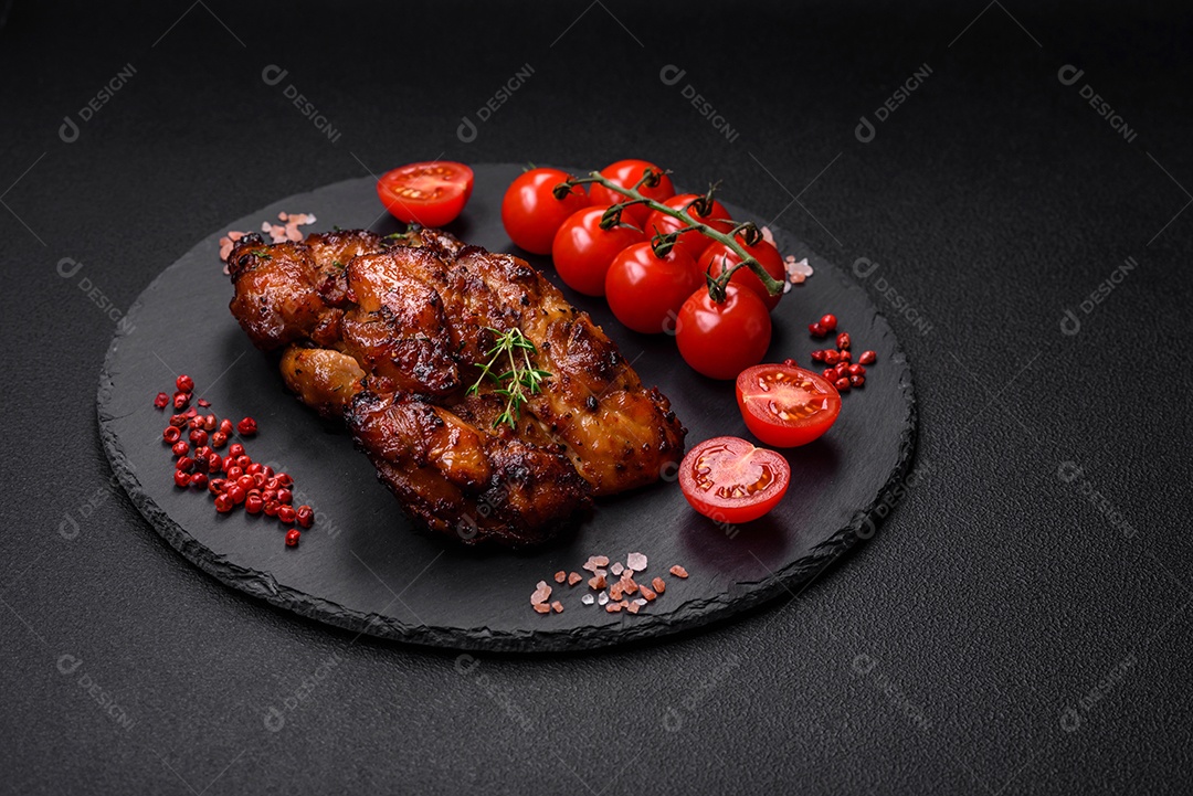 Deliciosa carne de frango assada com sal, especiarias e ervas sobre um fundo escuro de concreto