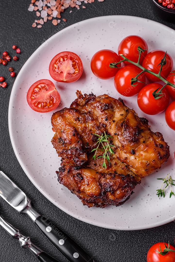 Deliciosa carne de frango assada com sal, especiarias e ervas sobre um fundo escuro de concreto