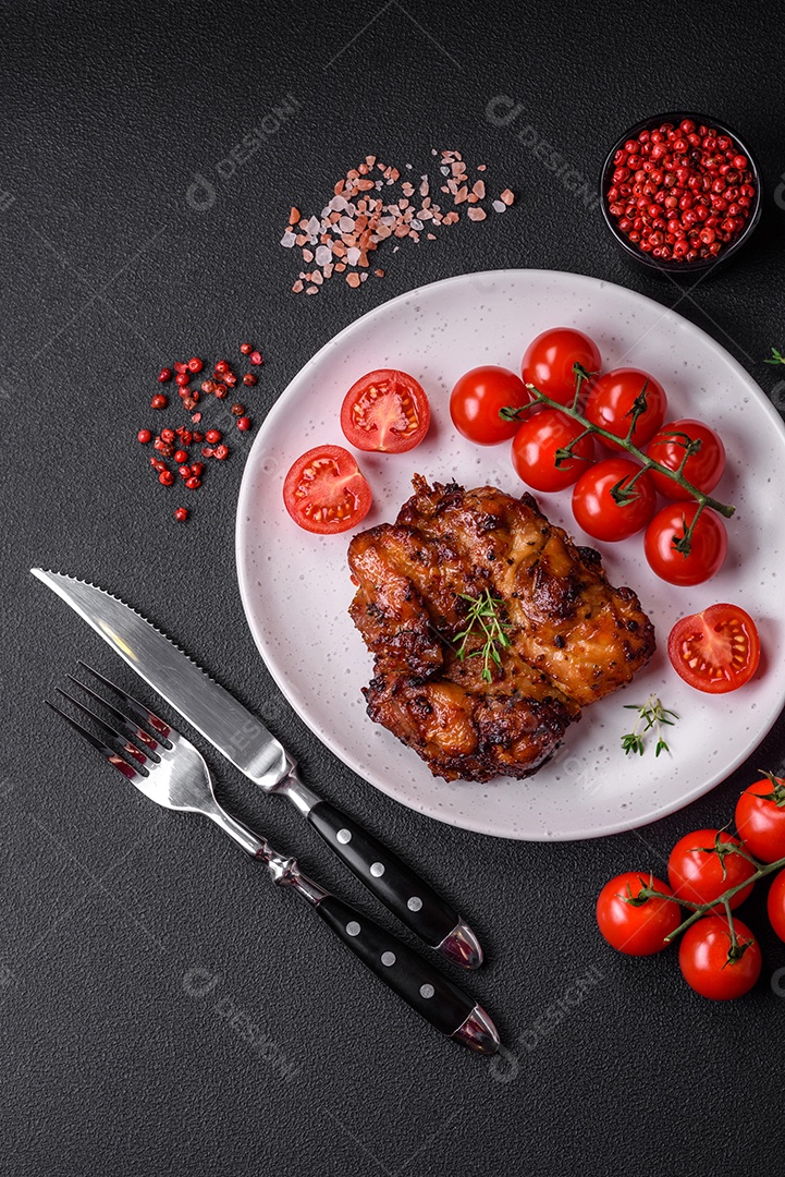 Deliciosa carne de frango assada com sal, especiarias e ervas sobre um fundo escuro de concreto