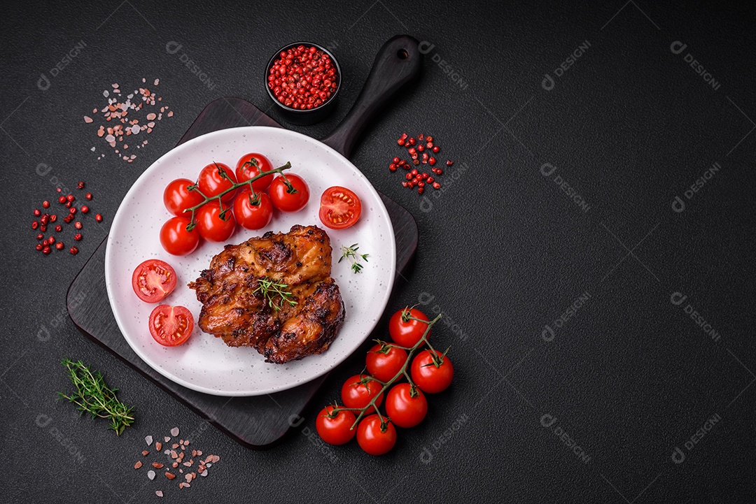 Deliciosa carne de frango assada com sal, especiarias e ervas sobre um fundo escuro de concreto