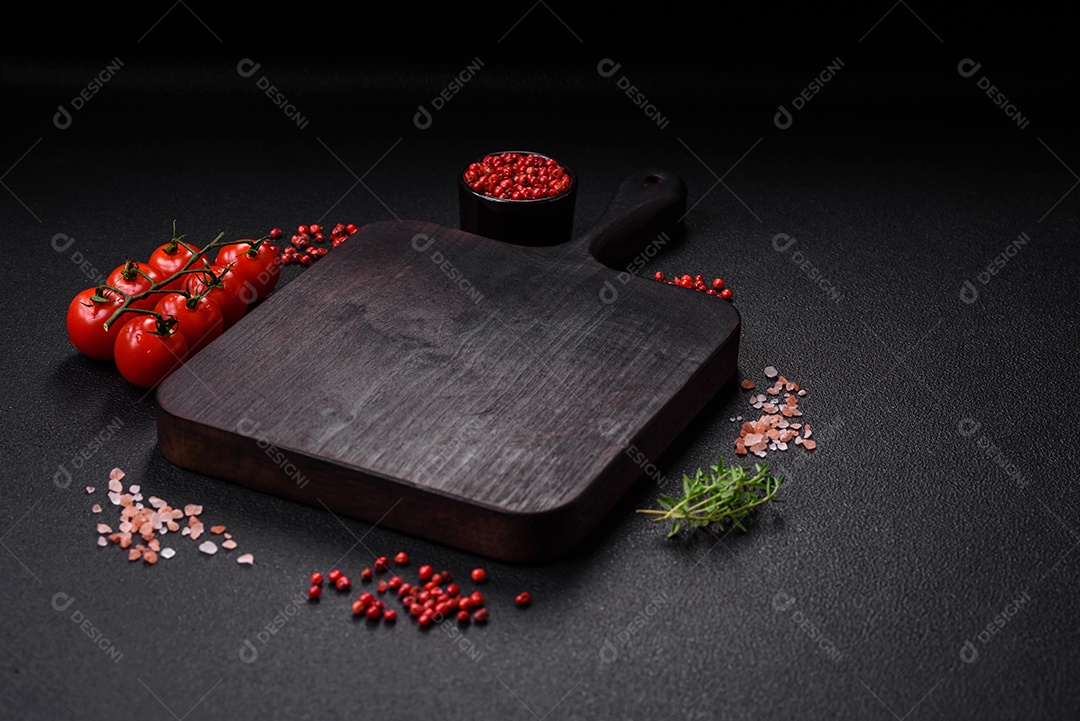 Deliciosos tomates cereja frescos nos galhos como ingrediente para cozinhar um prato vegetariano sobre um fundo escuro de concreto