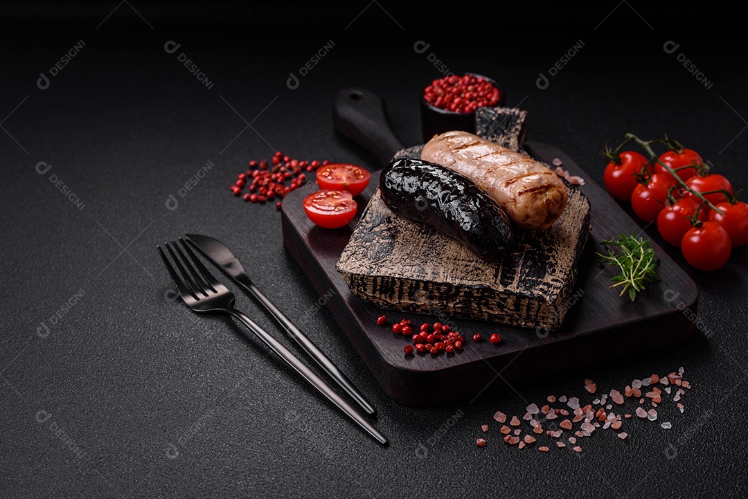 Deliciosas salsichas suculentas de diversas variedades grelhadas com sal, especiarias e ervas sobre um fundo escuro de concreto