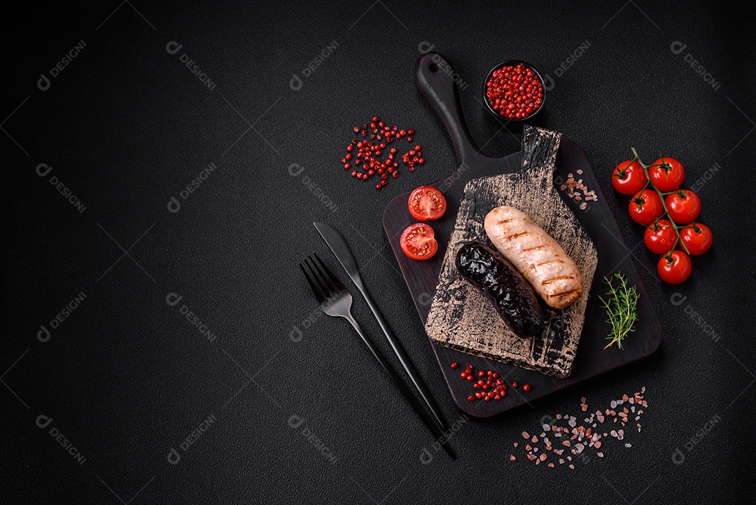 Deliciosas salsichas suculentas de diversas variedades grelhadas com sal, especiarias e ervas sobre um fundo escuro de concreto