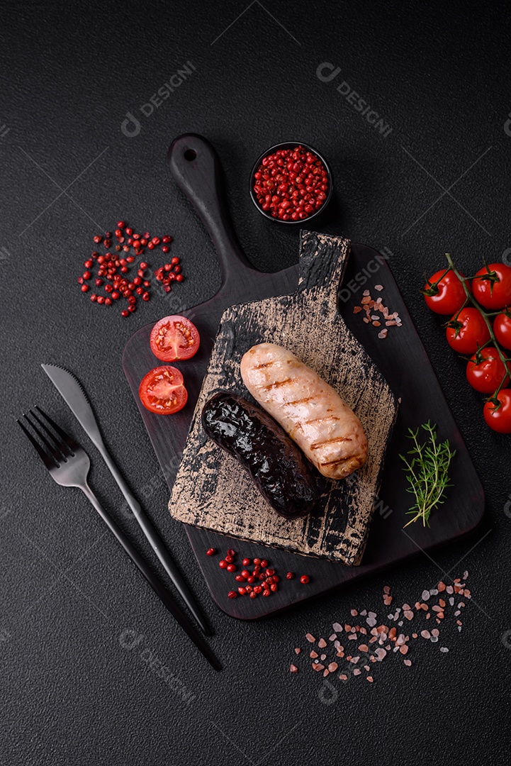 Deliciosas salsichas suculentas de diversas variedades grelhadas com sal, especiarias e ervas sobre um fundo escuro de concreto