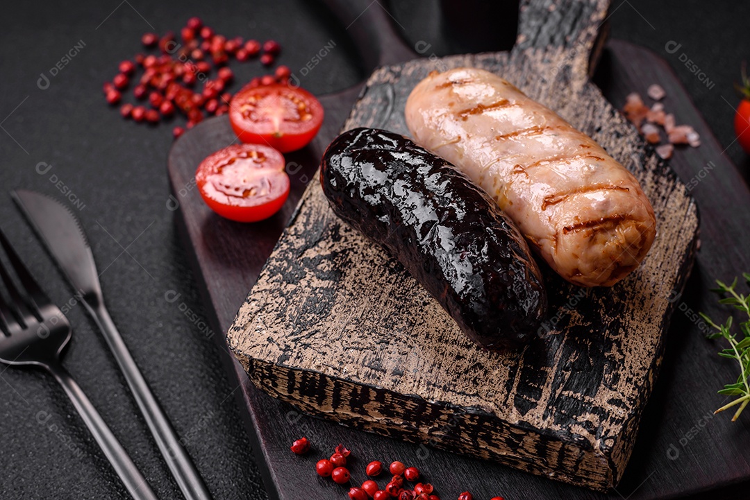 Deliciosas salsichas suculentas de diversas variedades grelhadas com sal, especiarias e ervas sobre um fundo escuro de concreto